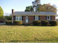 Charming brick home featuring a metal roof, neat landscaping, and a well-maintained front lawn at 1744 Prince Edward Dr, Elon, NC 27244