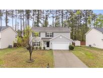 Charming two-story home featuring a well-maintained lawn, attached garage, and mature trees providing shade at 2214 Bayswater Dr, Creedmoor, NC 27522