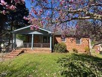 Charming brick home with covered porch, lush lawn and attractive flowering trees in a residential neighborhood at 24 Pine St, Franklinton, NC 27525