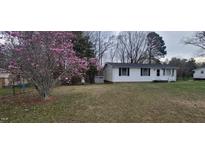 Quaint single-story home featuring white siding, dark shutters, and a blossoming magnolia tree in the front yard at 530 Broad Rd, Roxboro, NC 27573
