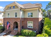 Beautiful townhome showcases classic brickwork, complemented by tan shingles and an inviting arched entrance, topped with an American flag at 714 Mordecai Towne Pl, Raleigh, NC 27604