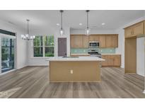 Bright kitchen features an island with quartz countertop, wooden cabinets, stainless appliances and hardwood floors at 858 Lake Artesia Ln, Fuquay Varina, NC 27526
