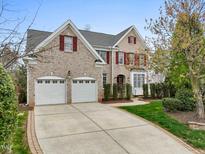 Beautiful two-story brick home featuring a well-manicured lawn, attached two-car garage, and red shutters at 9220 Meadow Mist Ct, Raleigh, NC 27617