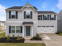 Charming two-story home features a well-manicured lawn, attached two-car garage, and a welcoming teal front door at 4524 Flat Bastion Drive Dr, Raleigh, NC 27610