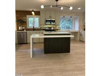 Bright kitchen features an island with white countertop, custom cabinets, and modern lighting at 4812 Latimer Rd, Raleigh, NC 27609