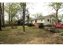 Charming ranch home with a brick foundation, covered carport, and beautiful flowering bushes and mature shade trees at 505 E Graham St, Mebane, NC 27302