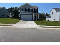 Charming two-story home with gray siding, a well-manicured lawn, and an attached two-car garage at 817 Kenyon Springs Dr, Zebulon, NC 27597