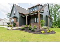 Beautiful two-story home with dark siding, brick accents, and well-manicured landscaping at 8620 Dukes Lake Rd, Zebulon, NC 27597