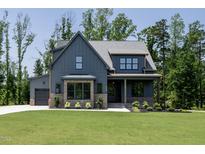Craftsman home featuring a gray facade, manicured lawn and landscape, and attached garage at 8620 Dukes Lake Rd, Zebulon, NC 27597
