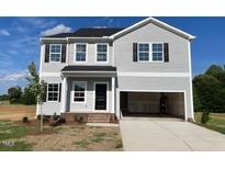 Two-story home with an attached two-car garage, light gray siding, and black shutters at 89 Grove Township Way, Angier, NC 27501