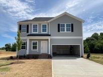 Two-story home featuring gray siding, black shutters and a two-car garage, set on a spacious lot at 89 Grove Township Way, Angier, NC 27501
