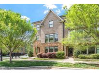 Inviting brick townhouse featuring manicured landscaping, stone accents, and mature trees at 1601 Bowery Dr, Raleigh, NC 27607
