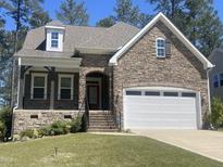 Charming stone-and-siding home with a two-car garage and covered porch nestled among mature trees at 171 School Side Dr, Spring Lake, NC 28390