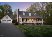 Charming home features a welcoming front porch, manicured lawn, and mature trees at twilight at 2259 Helena Moriah Rd, Timberlake, NC 27583