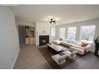 Bright living room features a fireplace, modern light fixture, and ample natural light from the many surrounding windows at 3244 Marcony Way, Raleigh, NC 27610