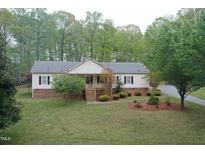 Charming single-story home features a welcoming front porch and is surrounded by mature trees and landscaping at 3954 Piney Grove Church Rd, Siler City, NC 27344