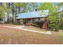 Charming home featuring a metal roof, lush landscaping, and a walkway through the trees to the back at 1355 Bowling Road, Fuquay Varina, NC 27526