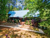 Charming wood home featuring a metal roof, lush landscaping, and a brick walkway to the front door at 1355 Bowling Road, Fuquay Varina, NC 27526