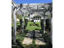 Beautiful backyard featuring a stone path and a pergola with lush landscaping at 255 Williamston Ridge Dr, Youngsville, NC 27596