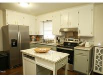 Updated kitchen boasts stainless steel appliances, bright white cabinets, and center island at 513 Orange St, Oxford, NC 27565