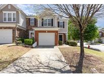 Charming townhome with a brick-accented facade, an attached garage, and a well-maintained front yard with mature landscaping at 8721 Owl Roost Pl, Raleigh, NC 27617