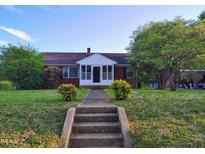 Charming brick home featuring a quaint front porch and well-maintained landscaping at 919 E Main St, Haw River, NC 27258
