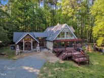 Stunning home featuring stone accents, dual-entry front doors, and a spacious deck, surrounded by lush greenery at 11209 Sedgefield Dr, Raleigh, NC 27613