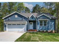 Charming exterior of a blue, single-story home with a manicured lawn and an attached garage at 115 Buckskin Dr, Louisburg, NC 27549