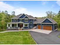 Stately two-story home with a covered porch, multi-car garage, and professionally landscaped yard at 255 Seven Island Rd, Pittsboro, NC 27312