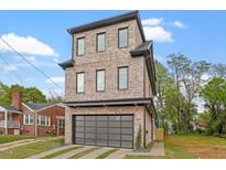 Modern three-story brick home with a black trim, garage, and neatly manicured lawn at 1007 E Davie St, Raleigh, NC 27601