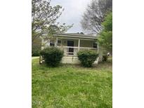 Charming single-story home with a cozy front porch surrounded by lush greenery and mature trees at 108 Virgil Rd, Durham, NC 27703