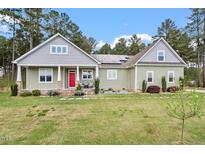 Beautiful home featuring a landscaped front yard, gray and green siding, and solar panels on the roof at 115 Mill Run Ln, Sanford, NC 27330