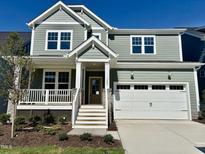 Charming two-story home featuring a welcoming front porch, two-car garage, and manicured landscaping at 1245 Porters Call Dr, Wendell, NC 27591