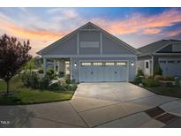 Charming home featuring a two-car garage, well-manicured lawn, and a beautiful sunset in the background at 21 Davidson St, Clayton, NC 27527