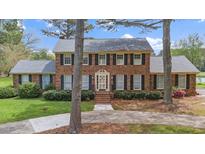 Traditional brick home with black shutters, manicured landscaping, and mature trees lining the walkway at 254 Pine Forest Dr, Siler City, NC 27344