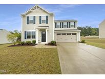 Charming two-story home boasts a classic design, complemented by a well-manicured lawn and an inviting driveway at 32 Bellini Dr, Angier, NC 27501