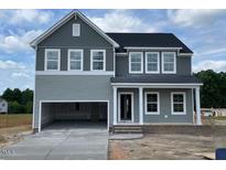 Charming two-story home featuring an open garage, gray siding, and a welcoming front porch with white columns at 54 Grove Township Way, Angier, NC 27501
