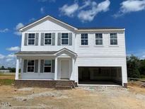 Charming two-story home with a welcoming front porch and an attached two-car garage at 59 Grove Township Way, Angier, NC 27501