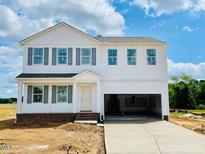 New construction two-story home featuring a white exterior, gray shutters, and a two-car garage under a cloudy blue sky at 59 Grove Township Way, Angier, NC 27501