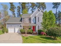 Charming two-story home with a vibrant red door, well-manicured lawn and an attached two-car garage at 709 Basil Dr, Durham, NC 27713