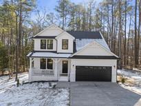 Charming two-story home with a black garage door, inviting front porch and landscaped yard at 7218 Sunrise Rd, Chapel Hill, NC 27514