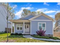 Charming exterior of a light blue bungalow with a welcoming front porch and manicured landscaping at 1008 Holloway St, Durham, NC 27701