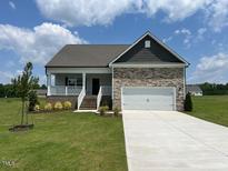 Charming single-story home featuring a stone facade, attached two-car garage, and well-manicured front lawn at 11450 International Dr, Middlesex, NC 27557