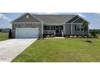 Inviting single-story home boasts a well-maintained lawn, two car garage and stone and gray vinyl siding at 11682 International Dr, Middlesex, NC 27557