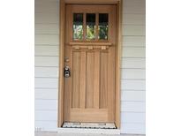 Stylish wood front door featuring three glass panels and modern hardware against a white wall at 2654 Lawndale, Durham, NC 27705