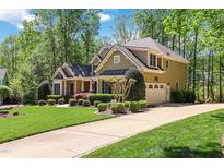 Traditional two-story home with attached garage and driveway surrounded by mature trees and manicured landscaping at 572 W Walker Woods Ln, Clayton, NC 27527