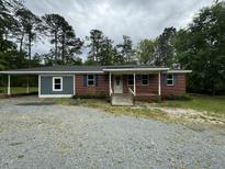 Charming brick home with a covered porch and ample parking on a gravel driveway at 8535 Us-301 S Hwy, Four Oaks, NC 27524