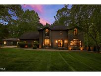 Elegant two-story home featuring arched windows and lush landscaping, lit by an inviting sunset at 10805 The Olde Pl, Raleigh, NC 27614