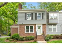 Charming townhouse with a brick facade, gray siding, black shutters, and landscaped front yard at 120 Barbary Ct, Cary, NC 27511