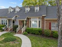 Charming brick townhome featuring manicured landscaping, dormer windows, and a welcoming front porch at 1234 Shadowbark Ct, Raleigh, NC 27603